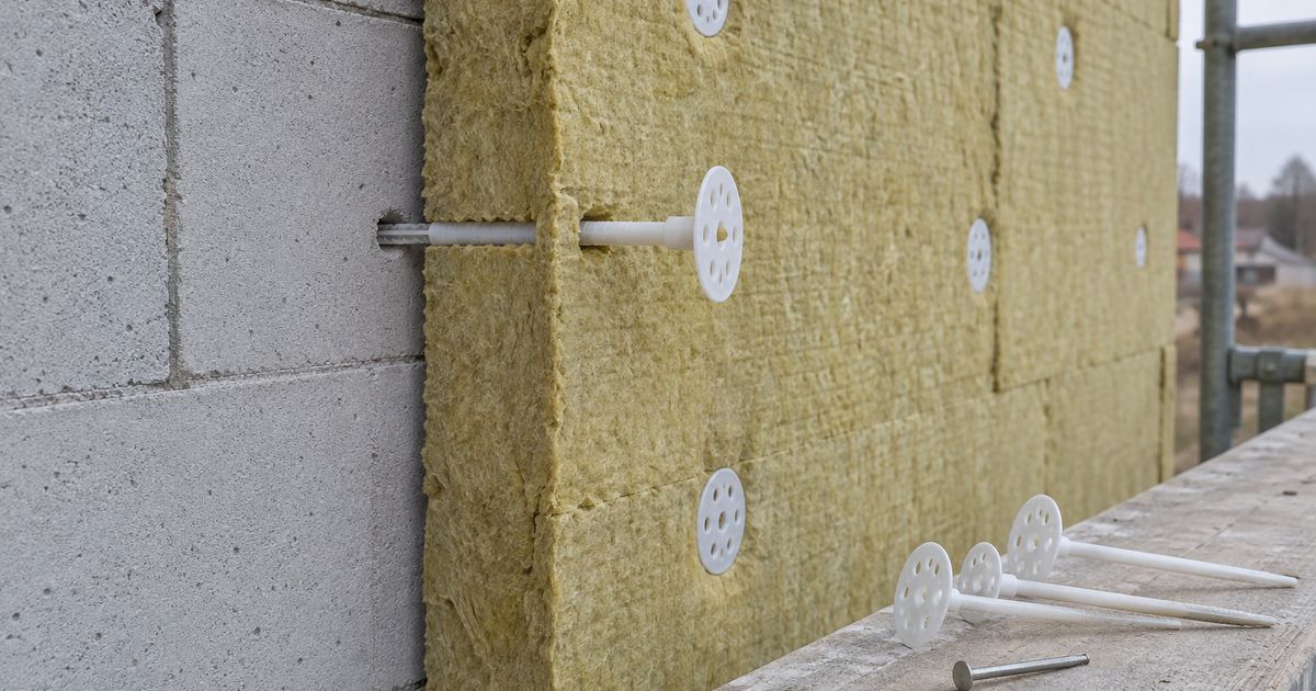 Тарельчатый дюбель проходит сквозь плиту минваты в отверстие в газоблоке; рядом дюбели разной длины на лесах